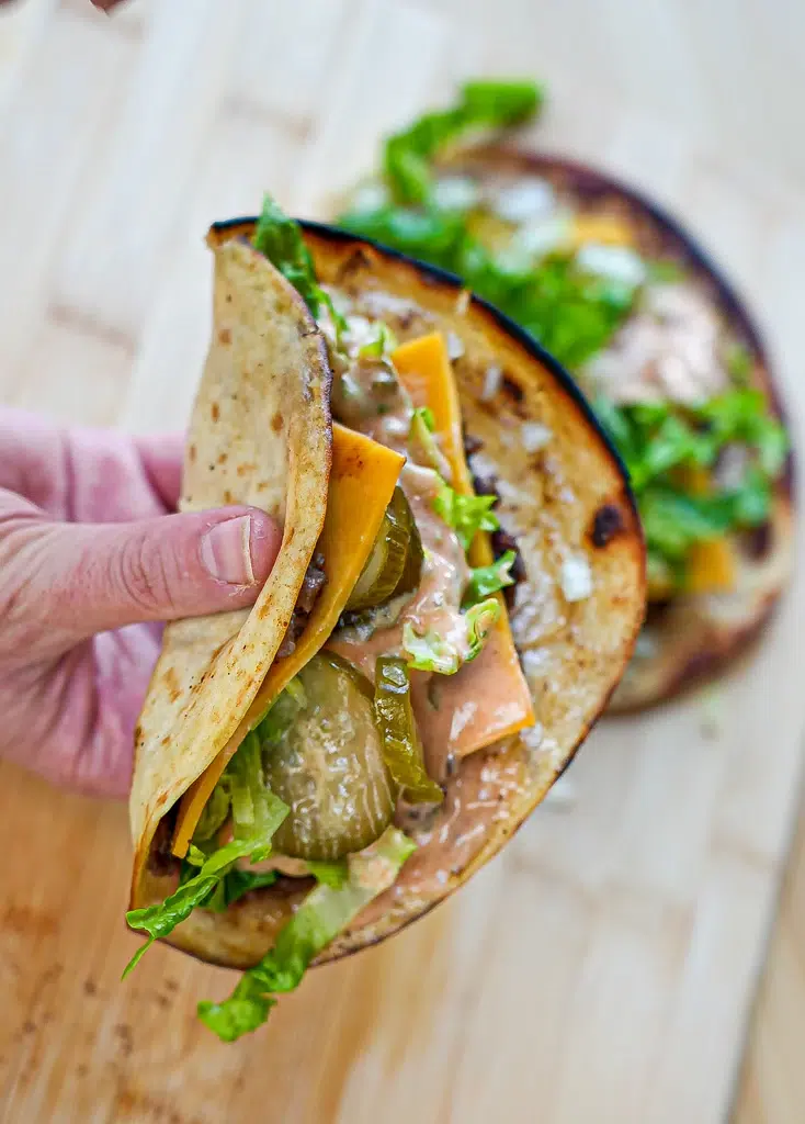 Big Mac tacos featuring seasoned beef, shredded lettuce, pickles, and a creamy sauce, served in soft taco shells.