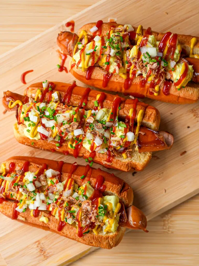 Hot dog buns are stuffed with curly frankfurt sausages, a curry-flavoured creamy potato salad and crispy fried shallots, then drizzled with ketchup and mustard.