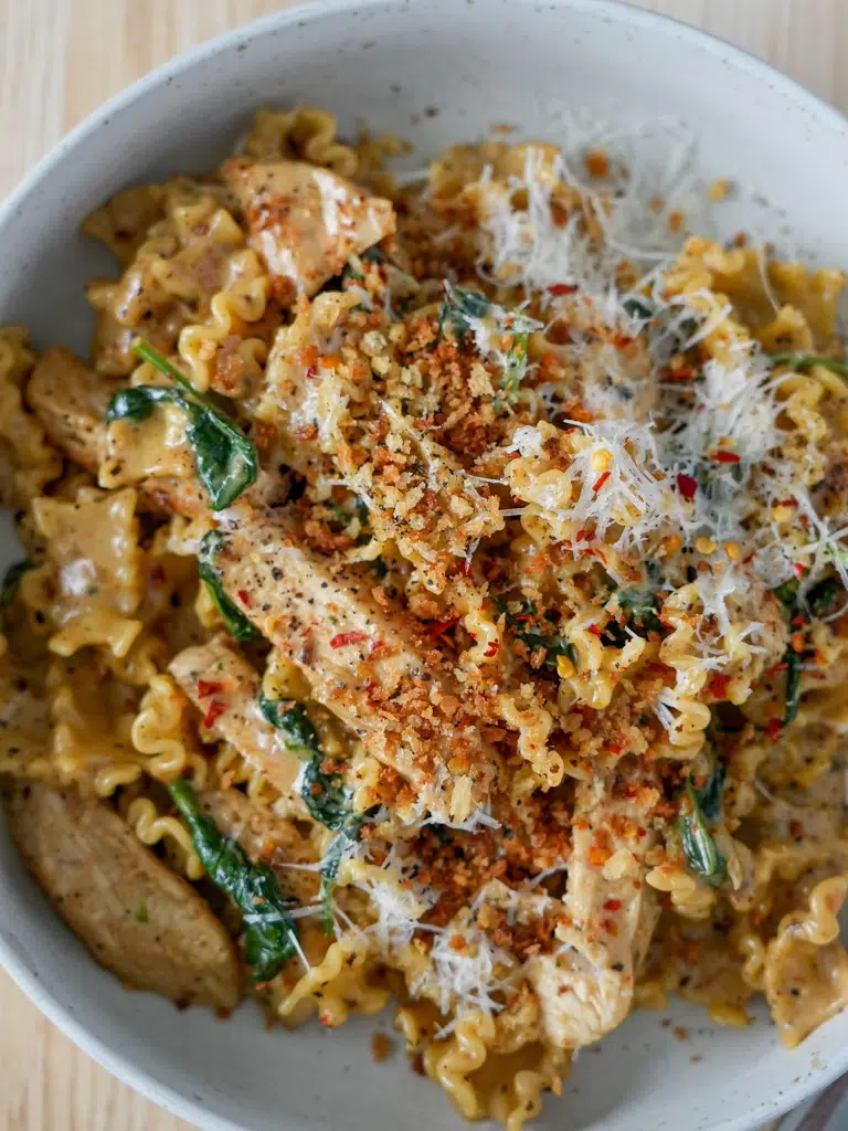Parmesan chicken pasta side plated with creamy sauce and fresh herbs.