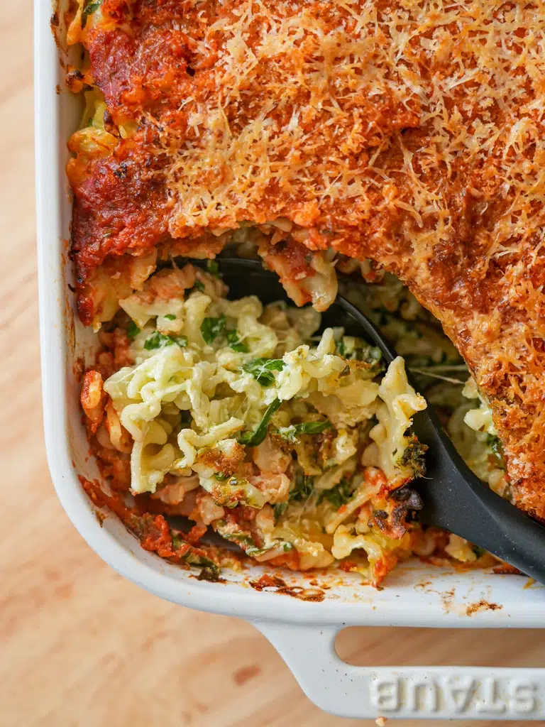 Close-up of a creamy spinach and cheese pasta bake, showcasing golden melted cheese and revealing the delicious filling inside.