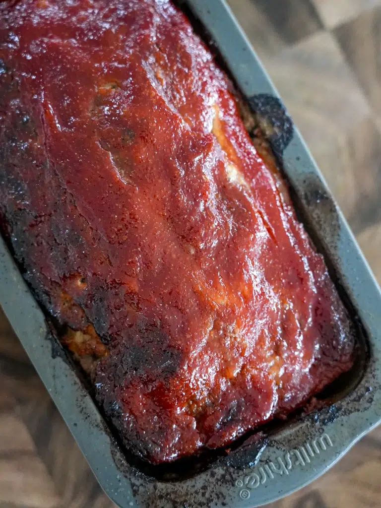 Meatloaf with a tangy tomato glaze freshly baked in a pan.