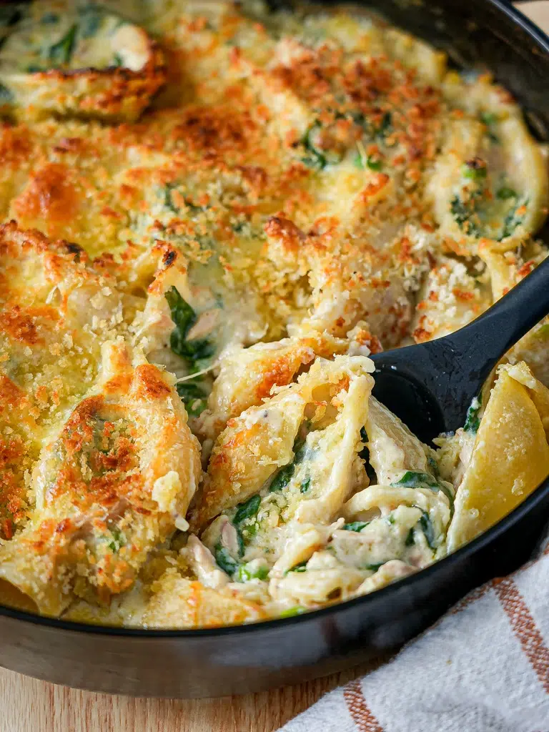 Close-up of Supercharged Tuna Mornay Pasta Bake in a pan with a spoon scooping a portion.