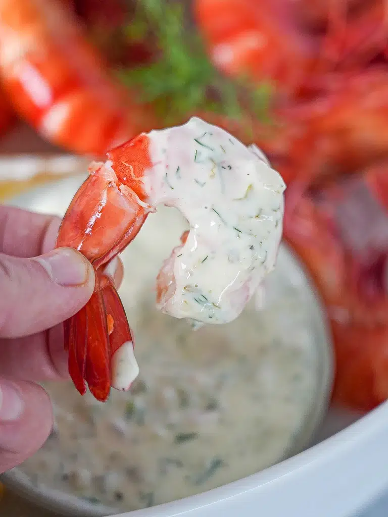 Close-up of a prawn dipped in tartare sauce, showcasing its creamy texture and fresh ingredients.