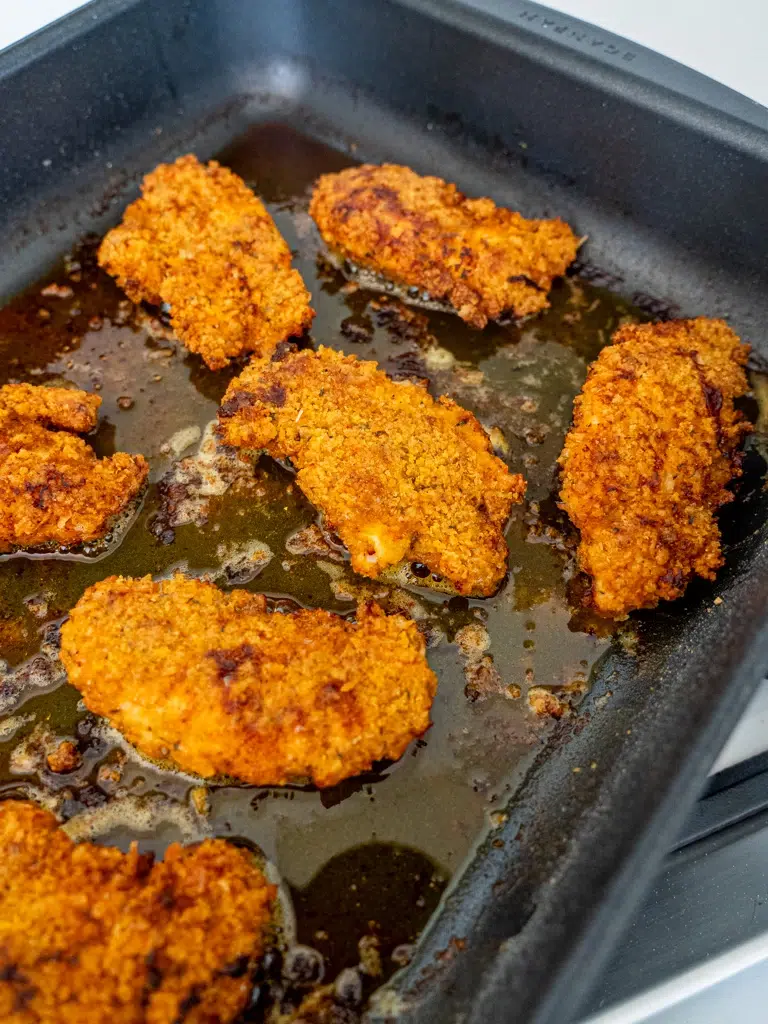 Overhead view of Southern-style baked chicken strips in a baking pan, perfectly golden and crispy.
