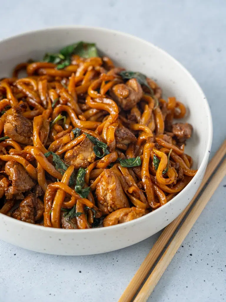 Close-up of a bowl of Three-Cup Chicken Noodles, featuring tender chicken, noodles, and a flavorful sauce.