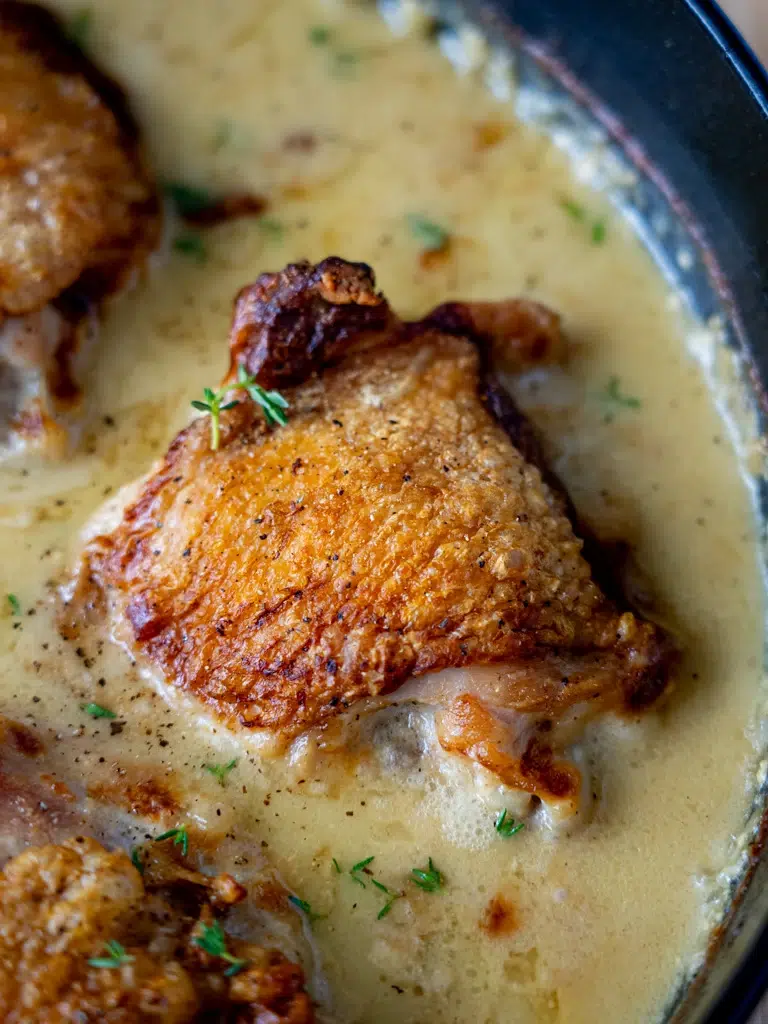 Close-up of baked Dijon chicken in a pan, coated in a rich sauce.