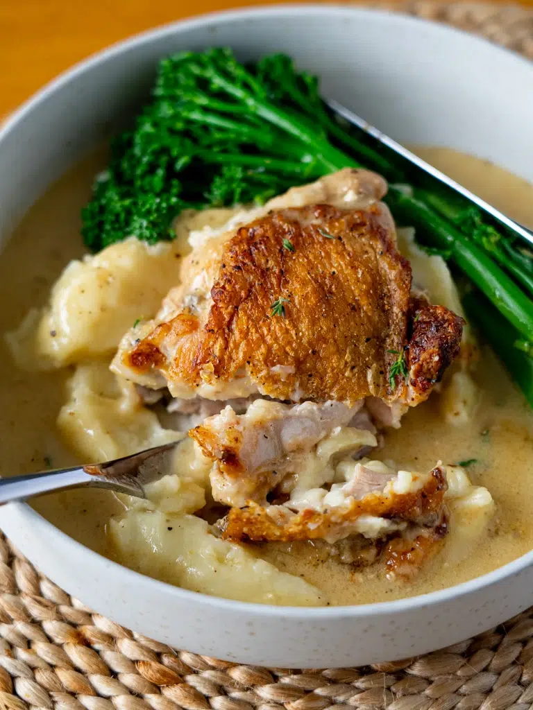 Close-up of a knife cutting into baked Dijon chicken, showcasing its juicy texture.