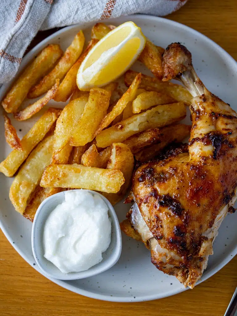 Overhead view of Portuguese chicken and chips on a plate.