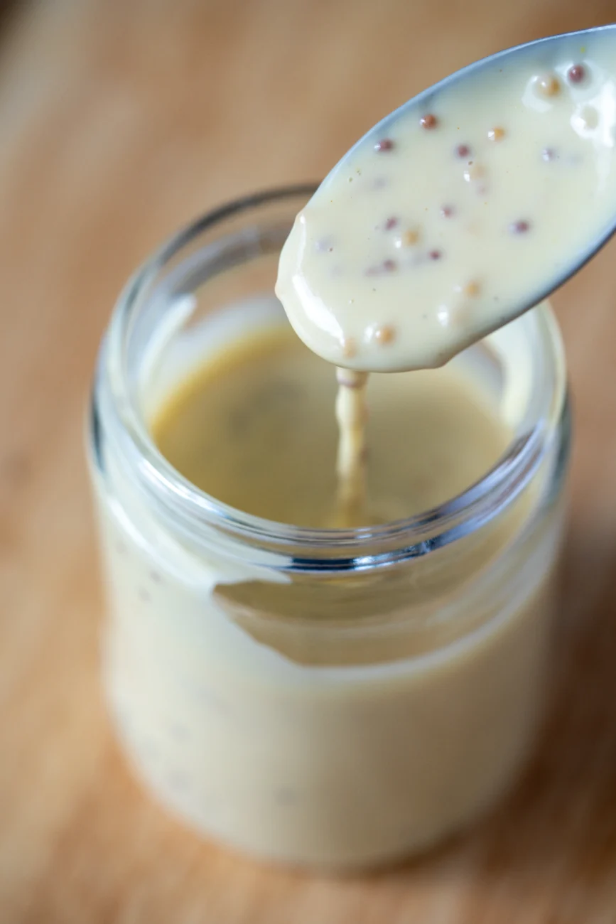 Honey mustard dipping sauce in a ramekin with spoon, close-up overhead view showing creamy texture.