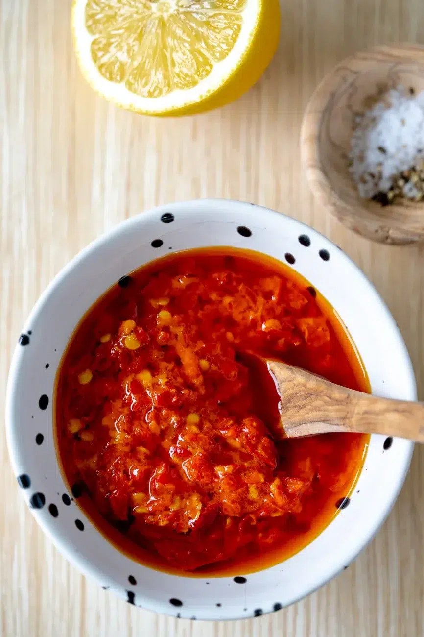 Close-up of Portuguese-style chili sauce in a small bowl with wooden spoon, mixed with lemon juice and salt