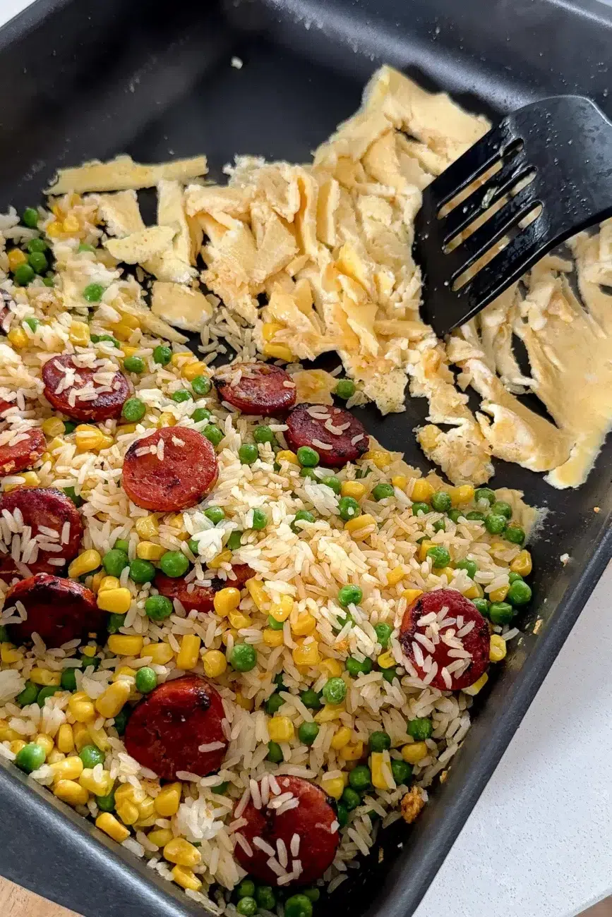 cooked egg mixture being broken up with spatula for fried rice recipe