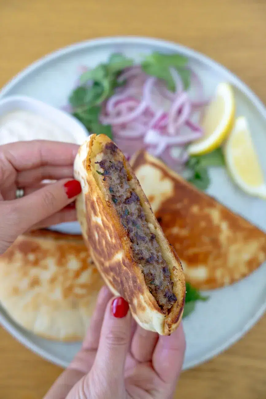 hands holding juicy stuffed pita arayes