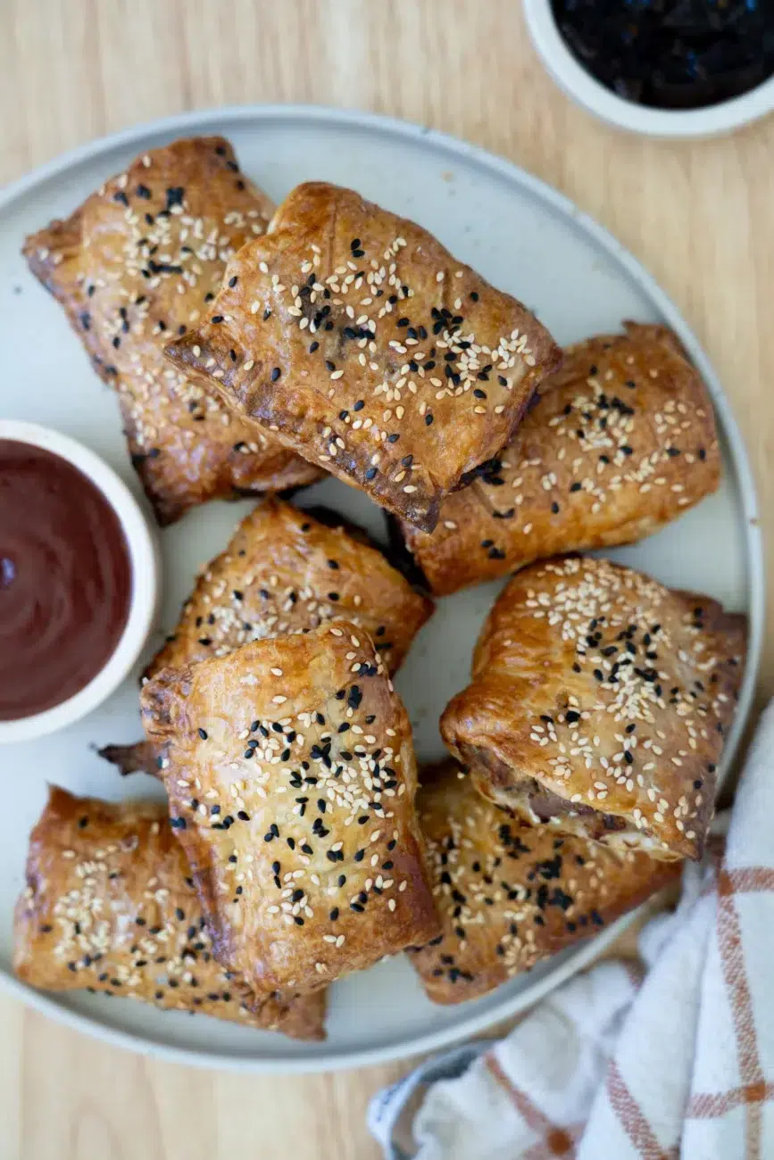 sausage rolls plated with ketchup and onion relish on side