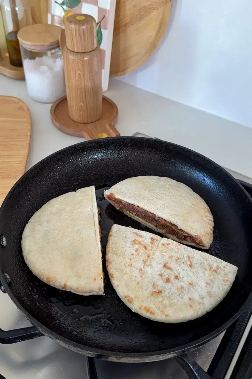 stuffed pita arayes being cooked in a pan three at a time