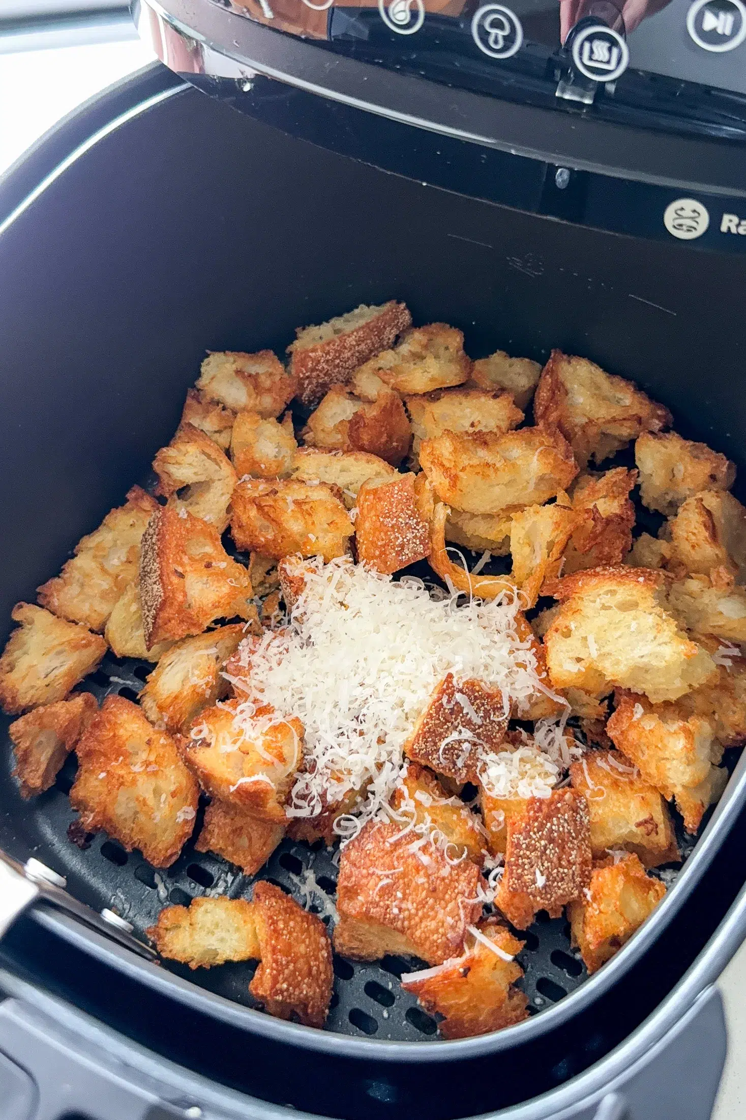 Garlic parmesan croutons cooking in the air fryer basket